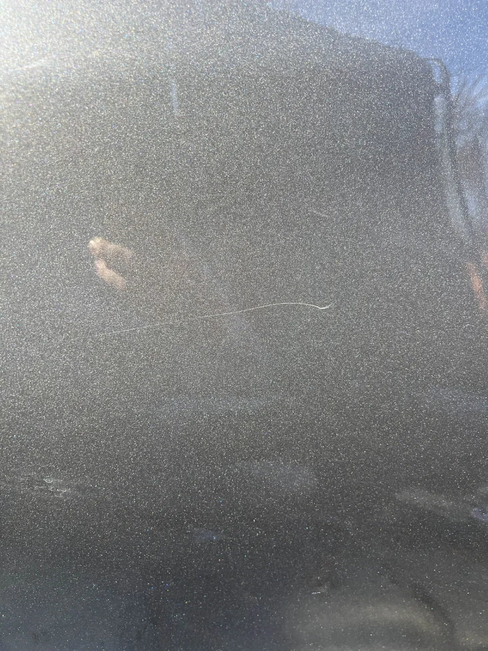 Close-up of a fine scratch and marring in the clear coat of the dark Lexus paint