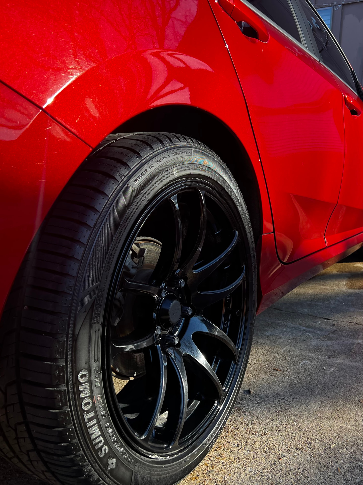 Close-up of the clean black wheel and dressed tire on the red Honda Civic